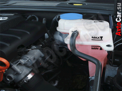 Бочек охлаждающей жидкости на фоне мотора, антифриз красного цвета - уровень охлаждающей жидкости в норме